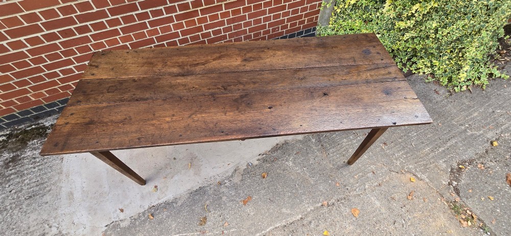 An antique rustic French wooden refectory dining table featuring a three-plank top, single side drawer, and square tapered legs. View XIII