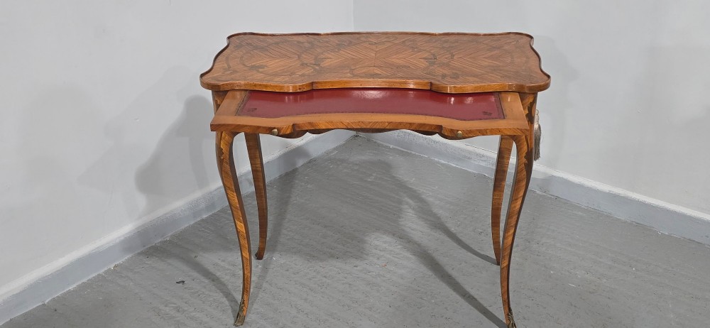 A small French Louis XV style writing table crafted from warm brown wood with scrolling marquetry, a serpentine edge, and slim cabriole legs. View V