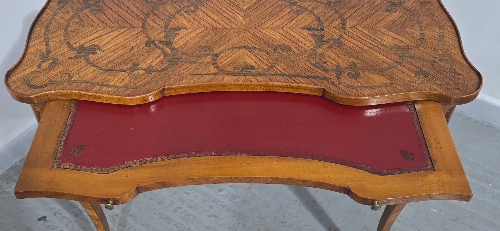 A small French Louis XV style writing table crafted from warm brown wood with scrolling marquetry, a serpentine edge, and slim cabriole legs. View VI