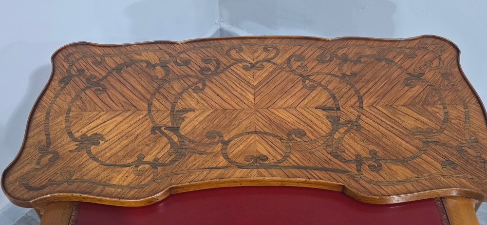 A small French Louis XV style writing table crafted from warm brown wood with scrolling marquetry, a serpentine edge, and slim cabriole legs. View VII