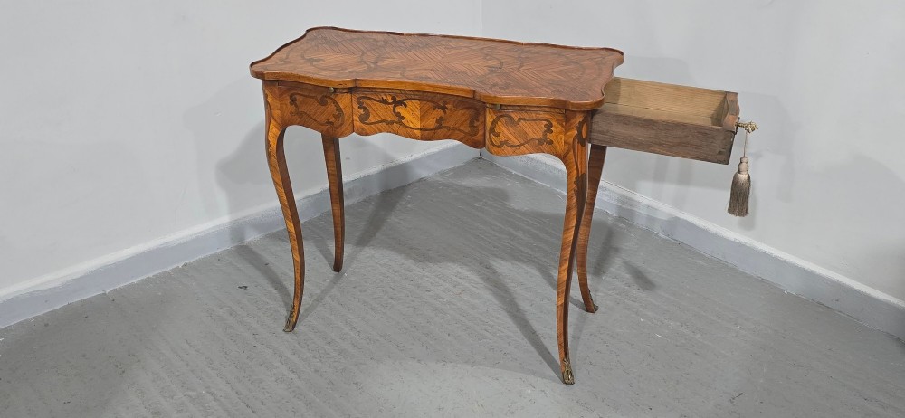 A small French Louis XV style writing table crafted from warm brown wood with scrolling marquetry, a serpentine edge, and slim cabriole legs. View VIII