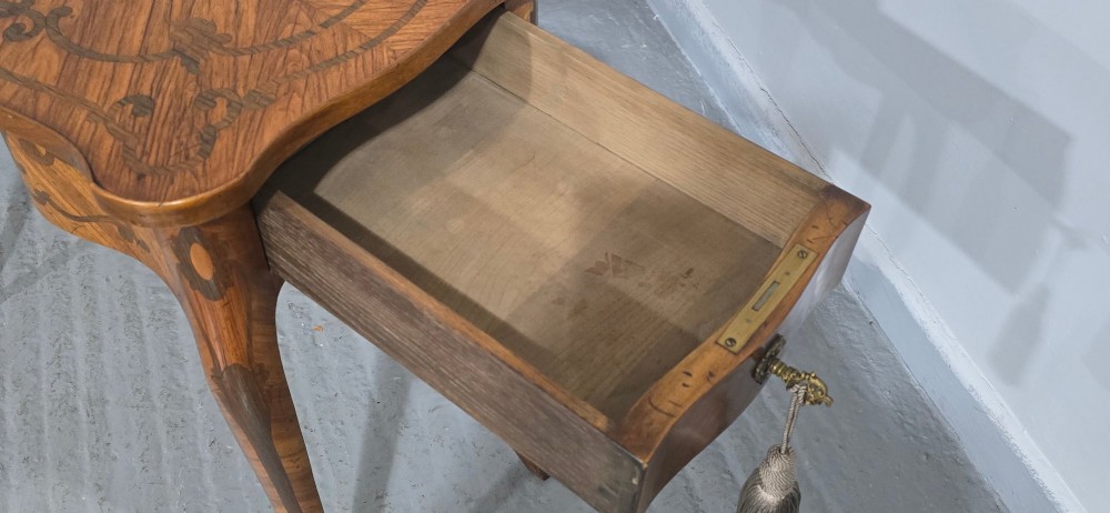 A small French Louis XV style writing table crafted from warm brown wood with scrolling marquetry, a serpentine edge, and slim cabriole legs. View IX