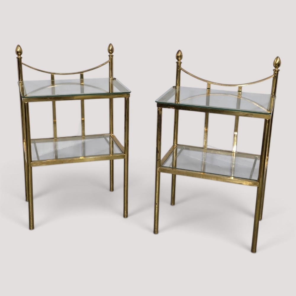 Pair of two-tier brass side tables with clear glass shelves and decorative finials.