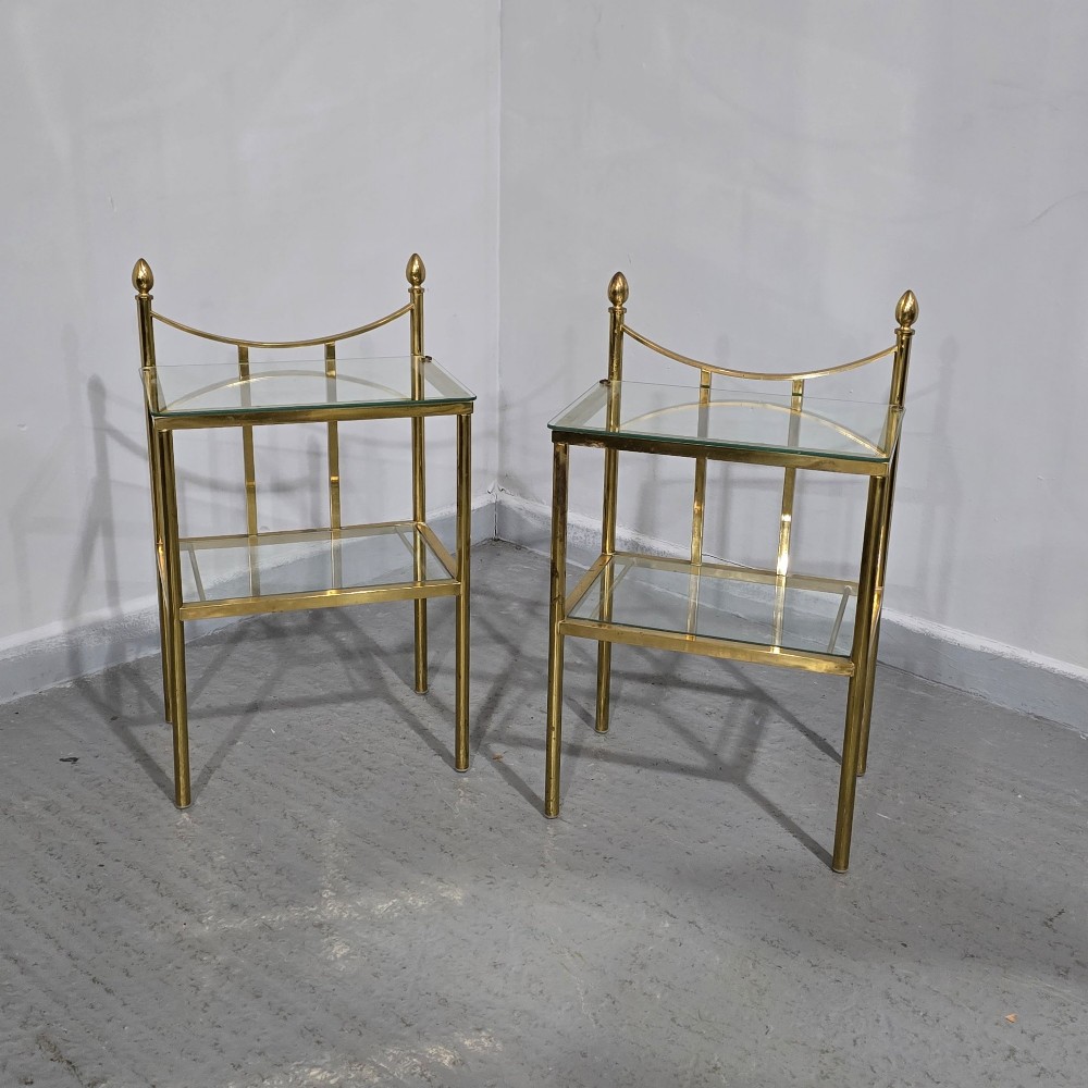 Pair of two-tier brass side tables with clear glass shelves and decorative finials. View II