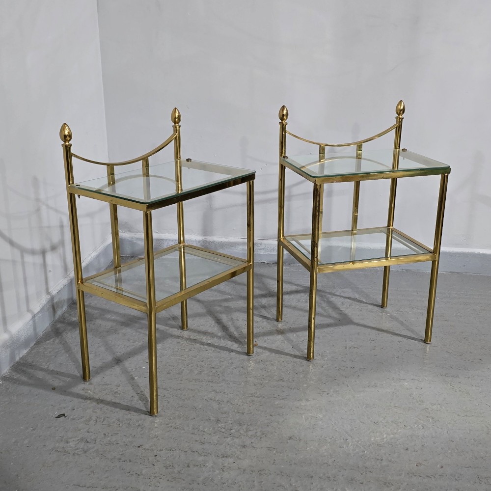 Pair of two-tier brass side tables with clear glass shelves and decorative finials. View IV