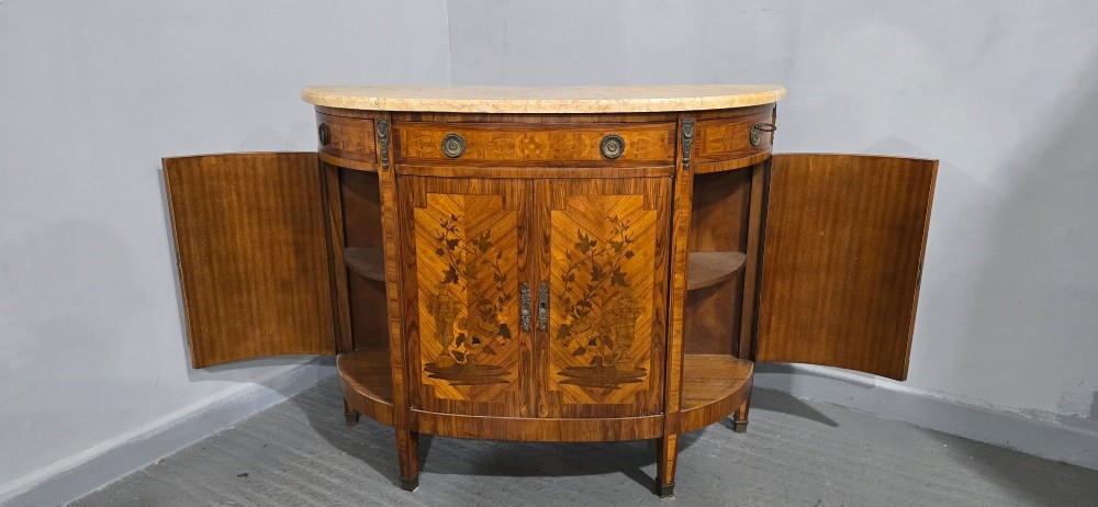 A French Louis XVI style demi-lune cabinet featuring intricate floral marquetry inlay, gilt-bronze mounts, and a contoured marble top. View X