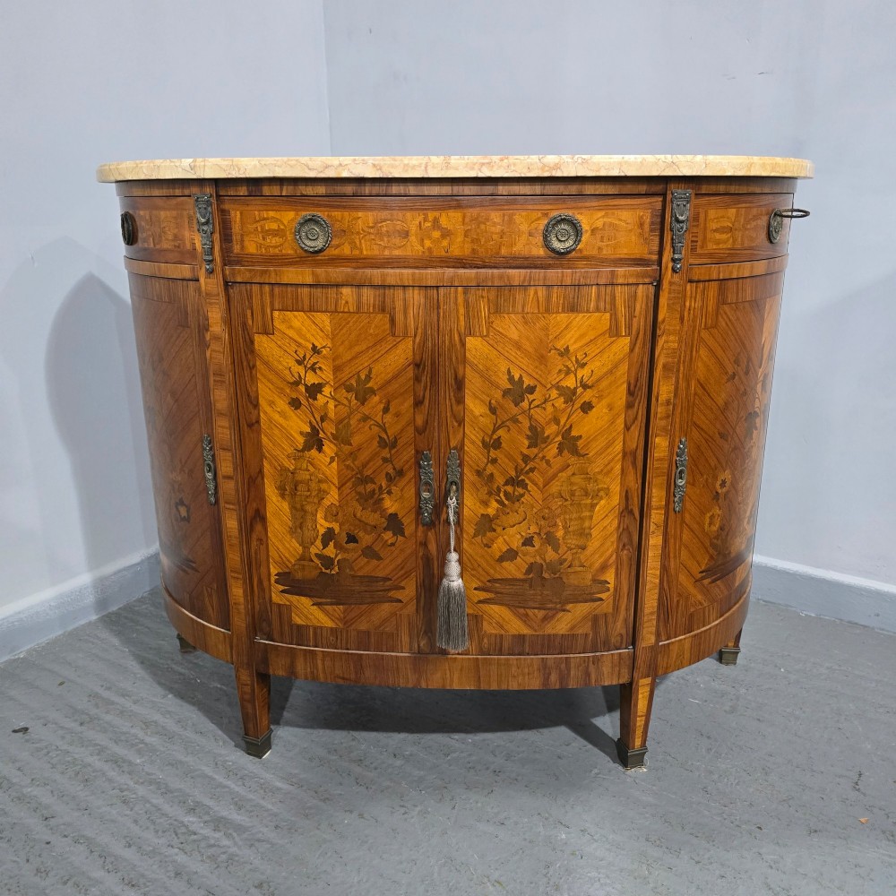 A French Louis XVI style demi-lune cabinet featuring intricate floral marquetry inlay, gilt-bronze mounts, and a contoured marble top. View XI