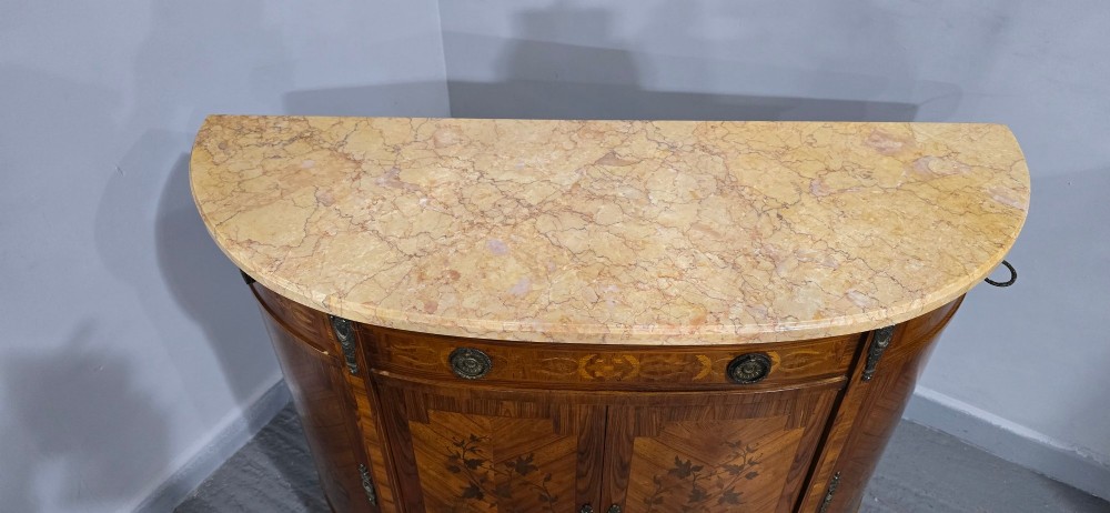 A French Louis XVI style demi-lune cabinet featuring intricate floral marquetry inlay, gilt-bronze mounts, and a contoured marble top. View XII