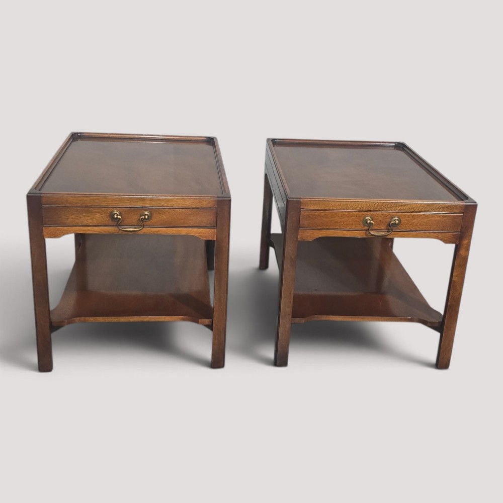 A pair of solid mahogany lamp end tables featuring tray tops, single drawers with brass handles, and lower tier shelves.