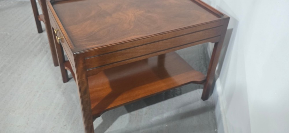 A pair of solid mahogany lamp end tables featuring tray tops, single drawers with brass handles, and lower tier shelves. View X