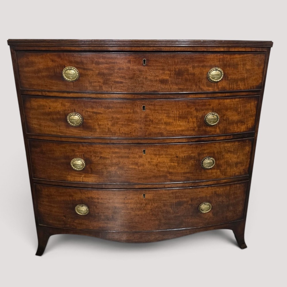 A Georgian mahogany bowfront chest of drawers featuring four graduated drawers with oval brass handles and splayed feet.