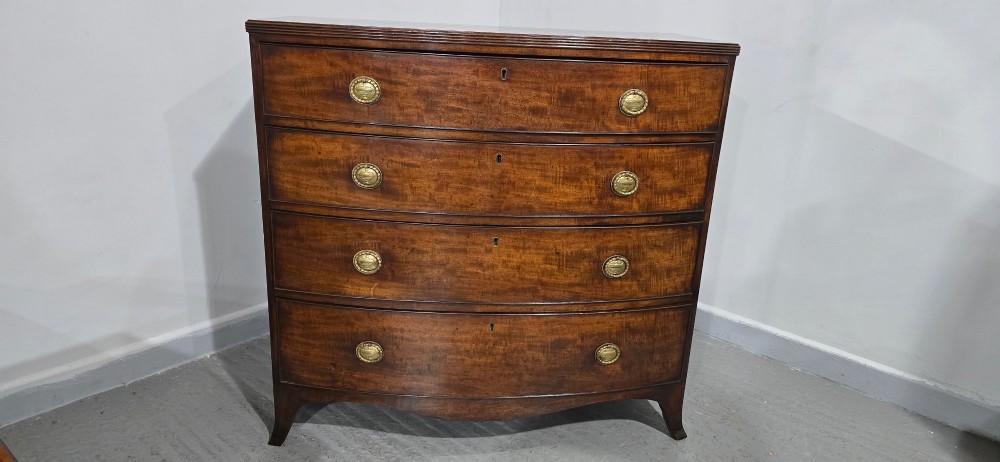 A Georgian mahogany bowfront chest of drawers featuring four graduated drawers with oval brass handles and splayed feet. View III