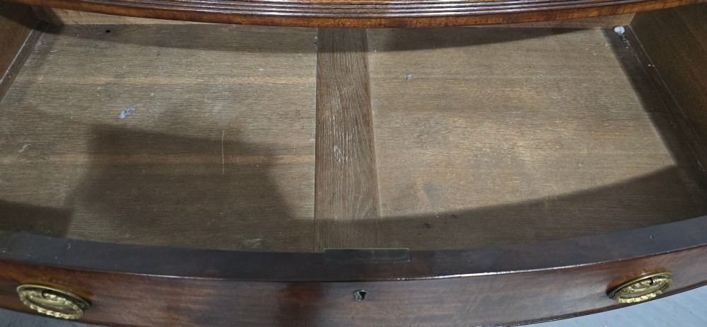 A Georgian mahogany bowfront chest of drawers featuring four graduated drawers with oval brass handles and splayed feet. View XI