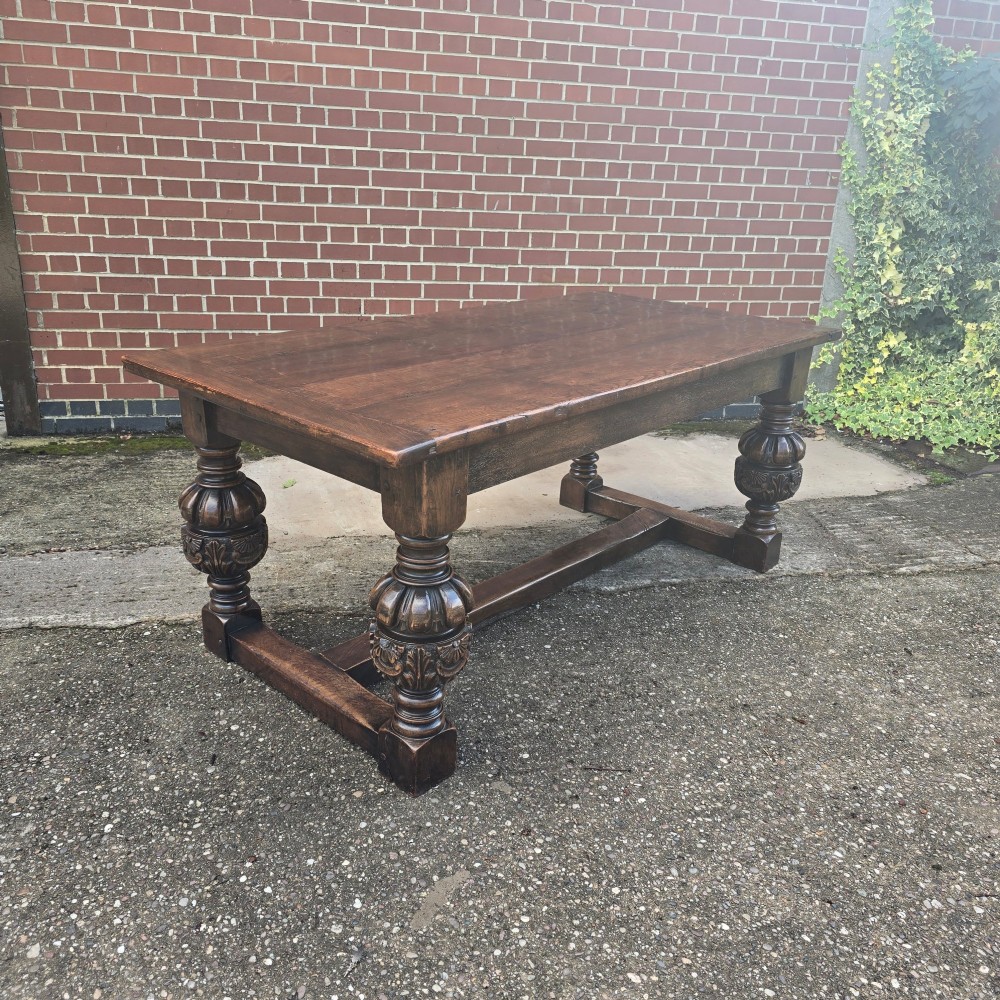 A heavy dark oak refectory dining table featuring carved cup-and-cover bulbous legs and a low stretcher base. View II