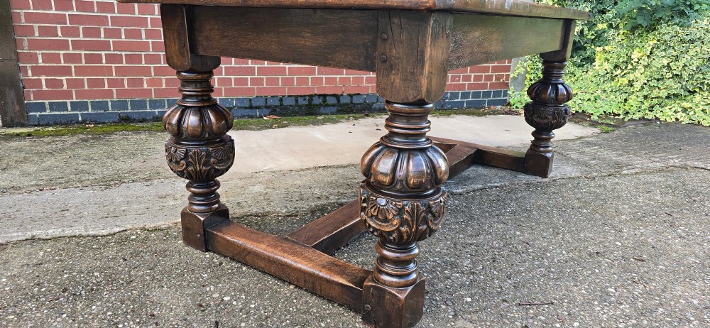 A heavy dark oak refectory dining table featuring carved cup-and-cover bulbous legs and a low stretcher base. View III