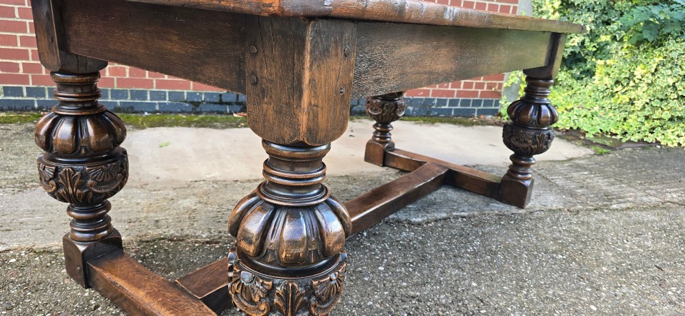 A heavy dark oak refectory dining table featuring carved cup-and-cover bulbous legs and a low stretcher base. View V