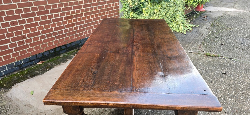 A heavy dark oak refectory dining table featuring carved cup-and-cover bulbous legs and a low stretcher base. View IX