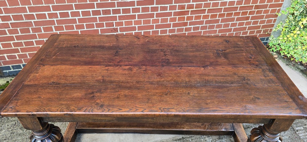 A heavy dark oak refectory dining table featuring carved cup-and-cover bulbous legs and a low stretcher base. View X