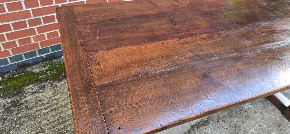A heavy dark oak refectory dining table featuring carved cup-and-cover bulbous legs and a low stretcher base. View XI