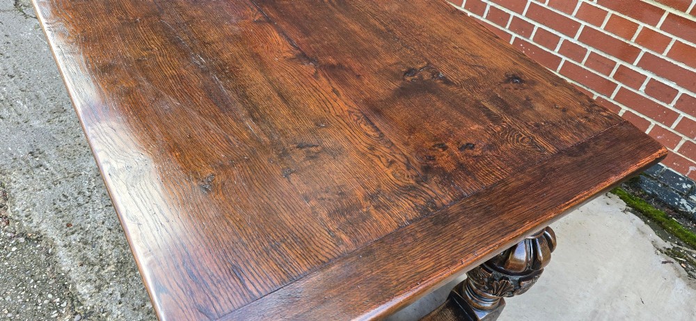 A heavy dark oak refectory dining table featuring carved cup-and-cover bulbous legs and a low stretcher base. View XII