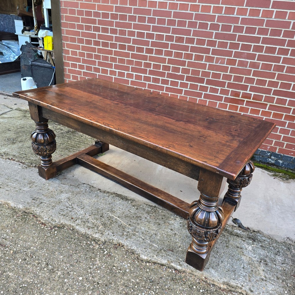 A heavy dark oak refectory dining table featuring carved cup-and-cover bulbous legs and a low stretcher base. View XV