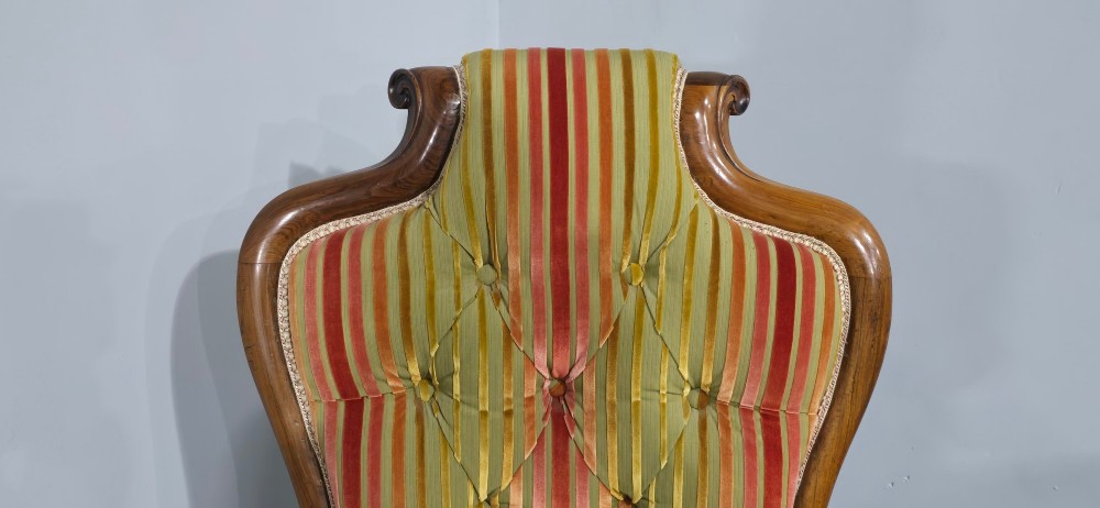 A Regency rosewood armchair featuring a button-tufted backrest, scrolled arms, carved legs, and striped green and red upholstery. View V