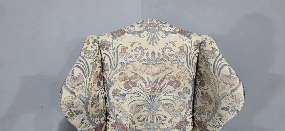 A high-backed wingback armchair upholstered in a botanical pattern with dark carved cabriole legs and ball-and-claw feet. View VI