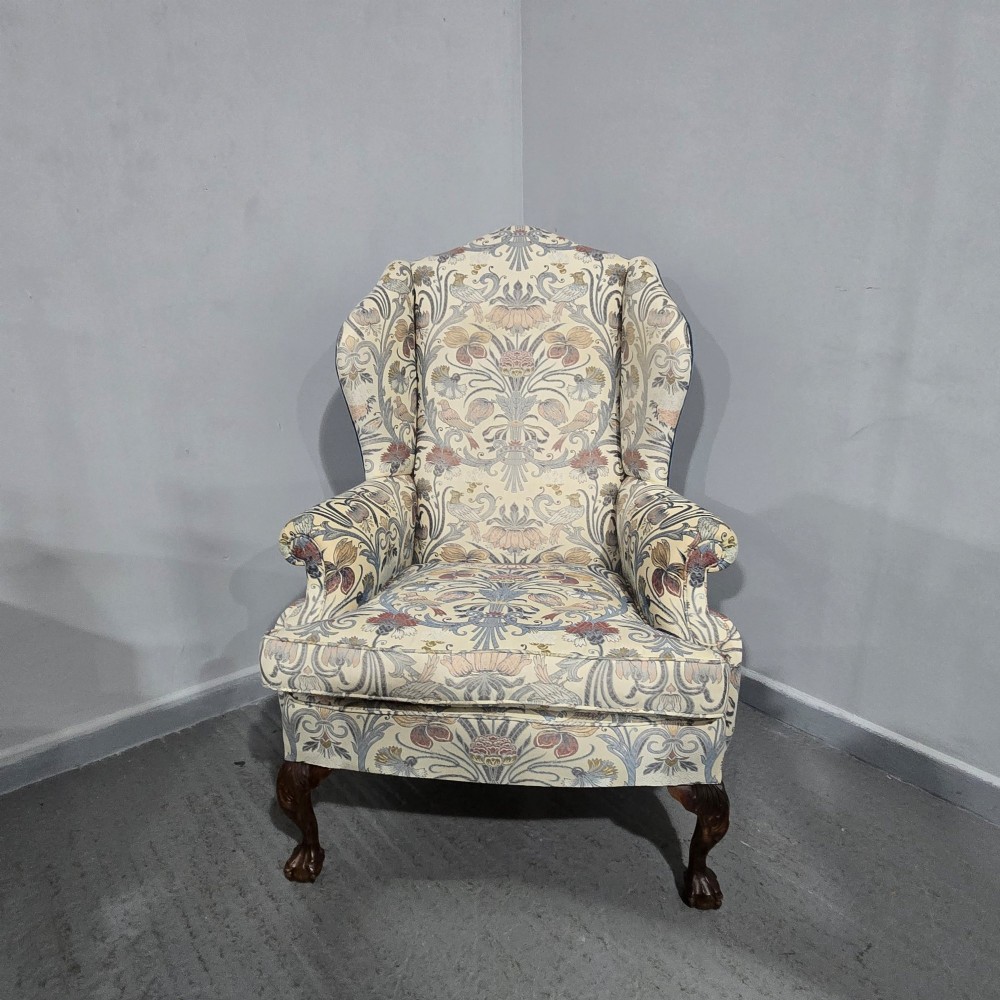 A high-backed wingback armchair upholstered in a botanical pattern with dark carved cabriole legs and ball-and-claw feet. View IX