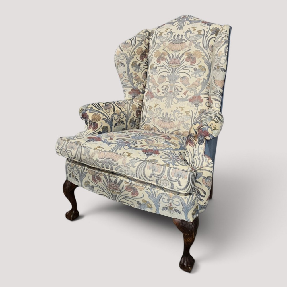 A high-backed wingback armchair upholstered in a botanical pattern with dark carved cabriole legs and ball-and-claw feet. View XI
