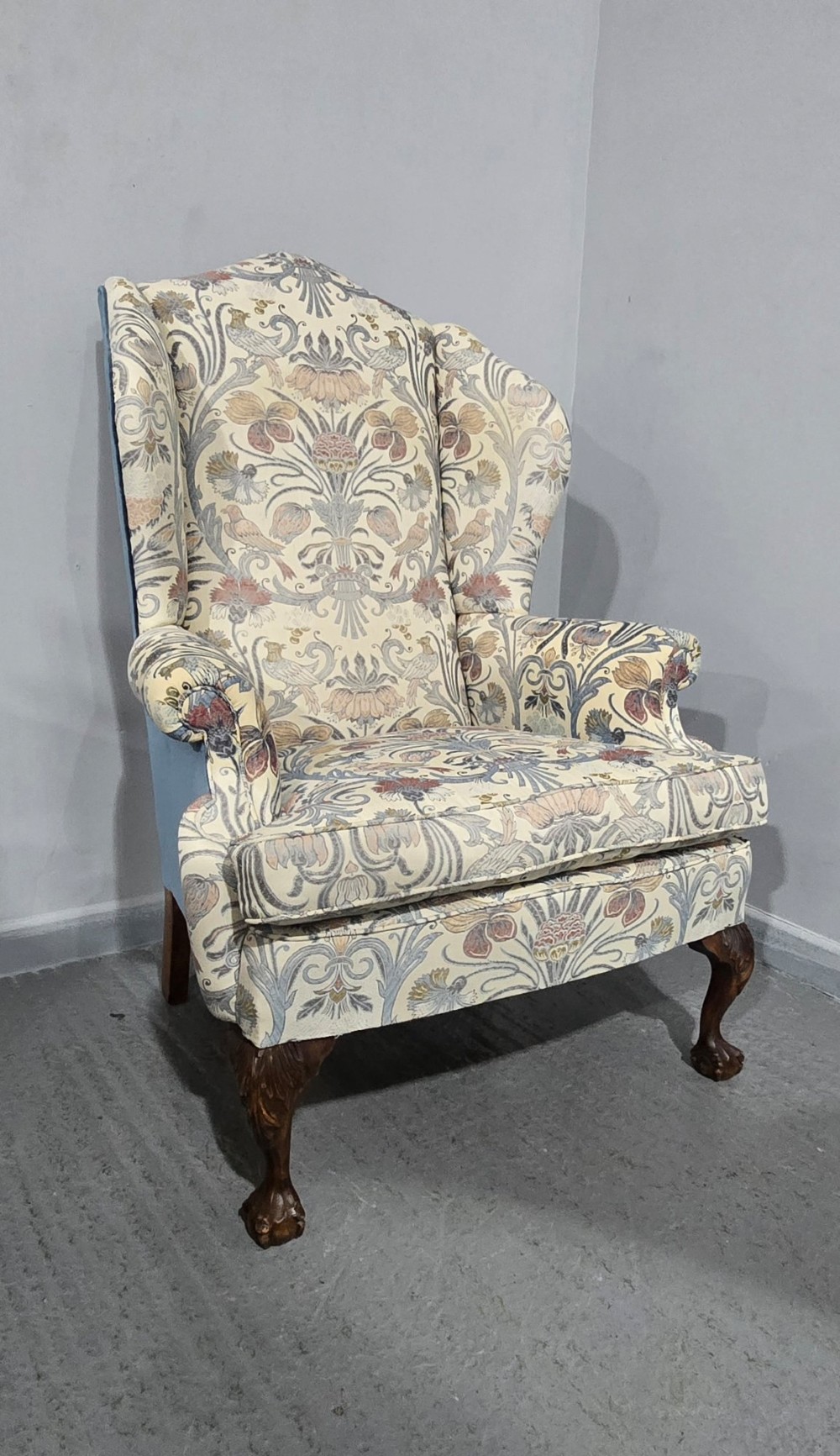 A high-backed wingback armchair upholstered in a botanical pattern with dark carved cabriole legs and ball-and-claw feet. View XII