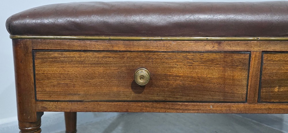 A Regency mahogany duet window stool with a brown leather seat, twin drawers, turned legs, and brass castors. View IV