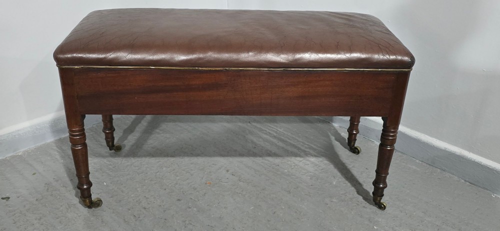 A Regency mahogany duet window stool with a brown leather seat, twin drawers, turned legs, and brass castors. View VIII