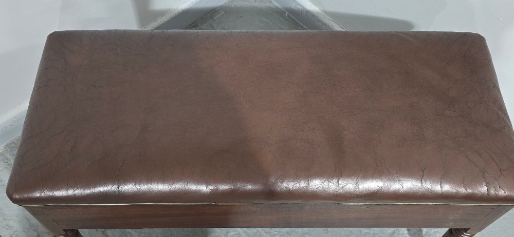 A Regency mahogany duet window stool with a brown leather seat, twin drawers, turned legs, and brass castors. View IX