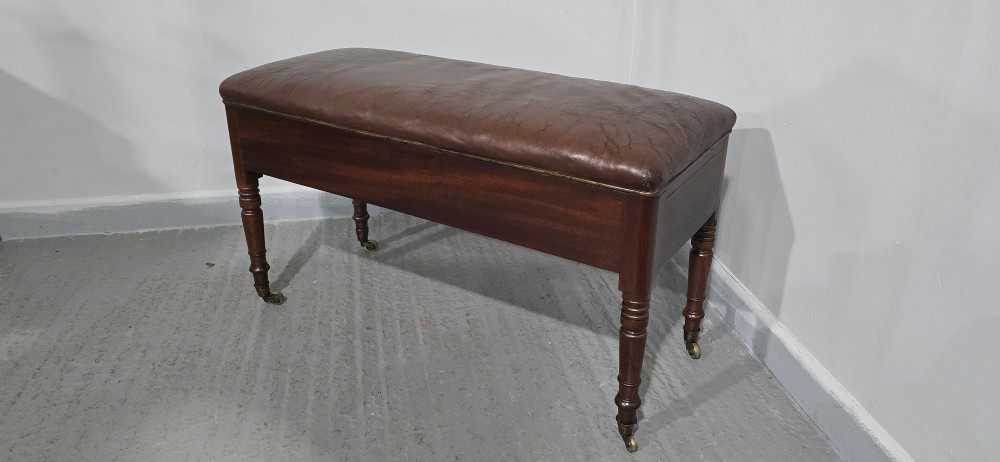 A Regency mahogany duet window stool with a brown leather seat, twin drawers, turned legs, and brass castors. View X