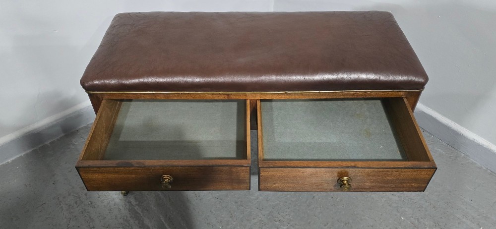 A Regency mahogany duet window stool with a brown leather seat, twin drawers, turned legs, and brass castors. View XI