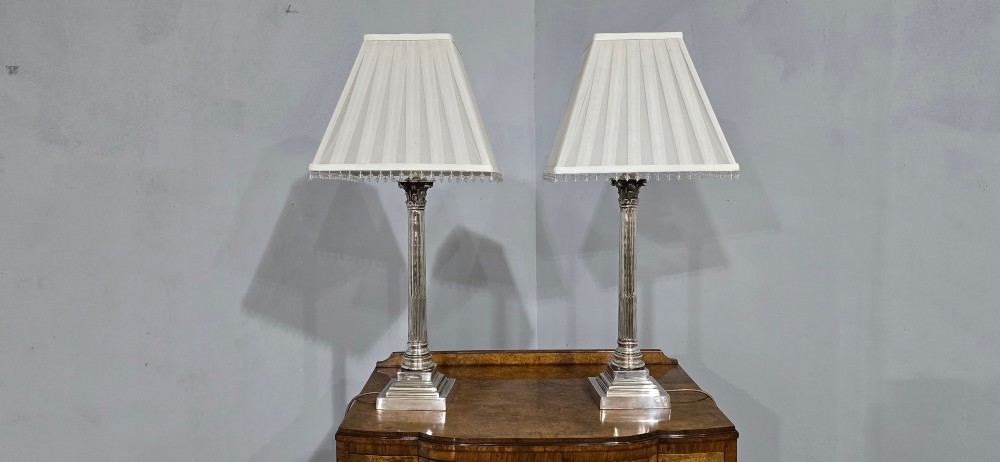 A pair of silver-plated neoclassical column table lamps with square stepped plinths and white pleated shades featuring beaded lower trim. View II