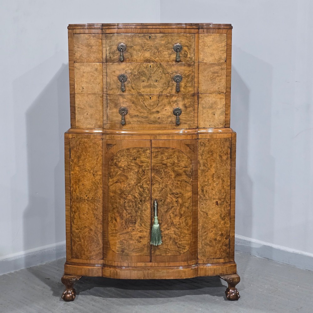 An antique burr walnut linen press featuring an upper drawer section and lower double-door cupboard supported by carved ball and claw feet. View II
