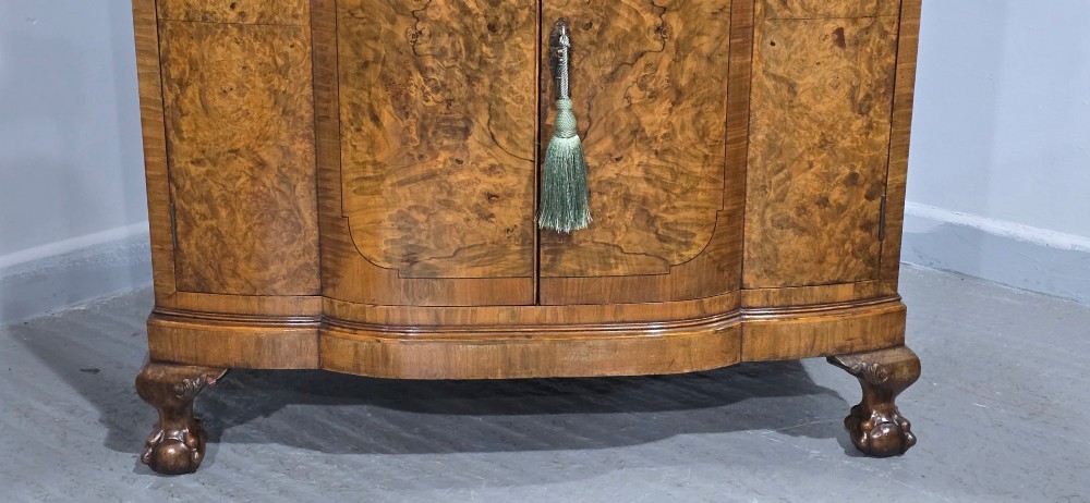 An antique burr walnut linen press featuring an upper drawer section and lower double-door cupboard supported by carved ball and claw feet. View III