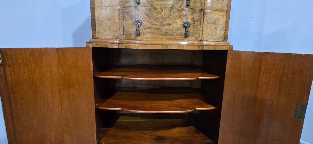 An antique burr walnut linen press featuring an upper drawer section and lower double-door cupboard supported by carved ball and claw feet. View XI