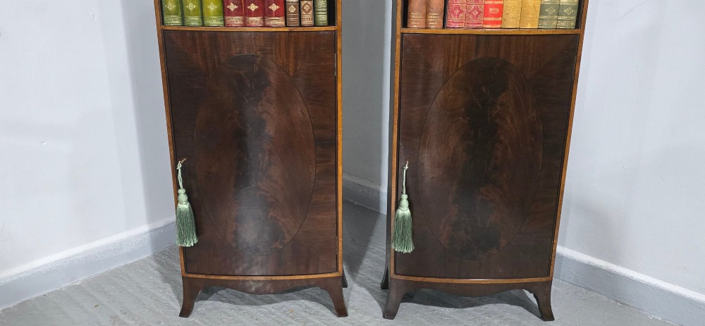 A pair of tall slim mahogany open bookcases featuring inlaid fan pediments, adjustable shelves, and curved lower cupboard doors. View IV