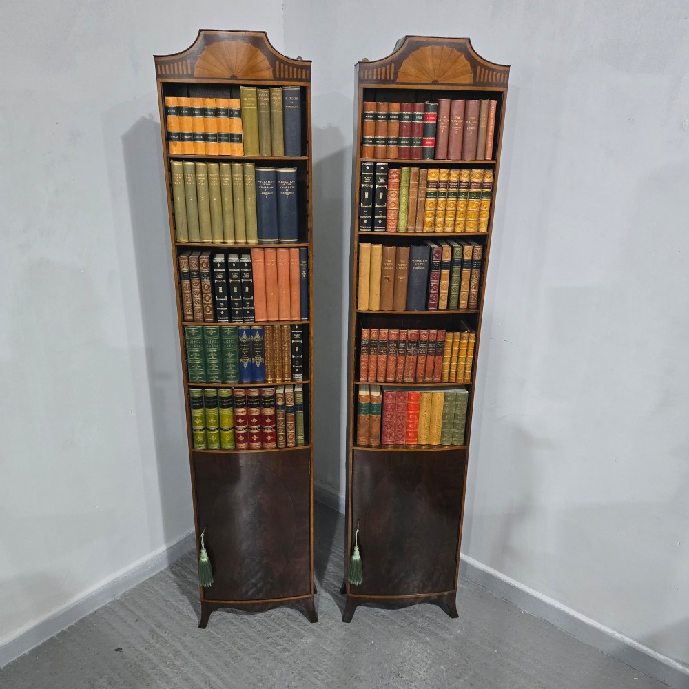 A pair of tall slim mahogany open bookcases featuring inlaid fan pediments, adjustable shelves, and curved lower cupboard doors. View VI