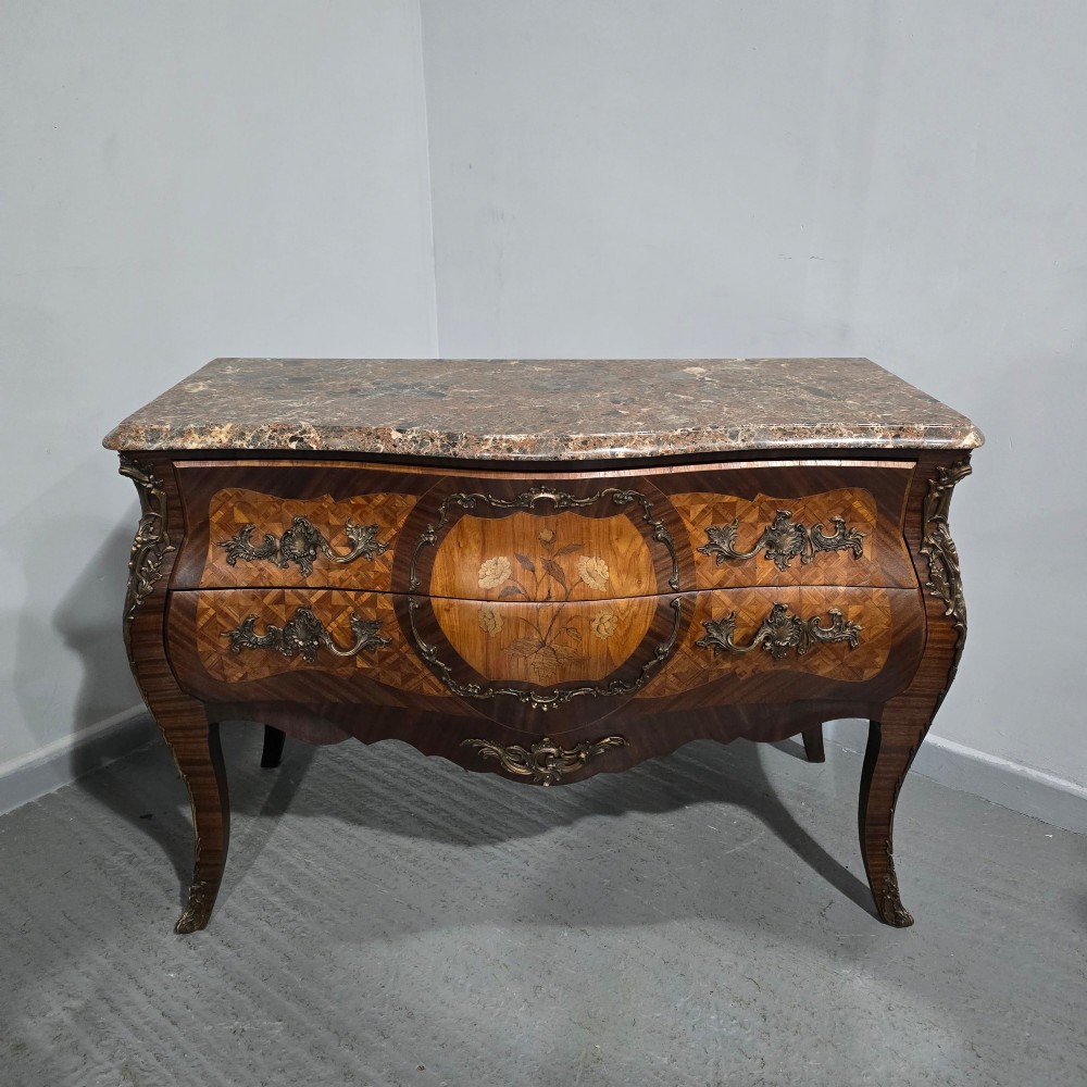 A French Louis XV style bombe commode featuring detailed floral marquetry inlay, bronze mounts, curved legs, and a brown marble top. View II