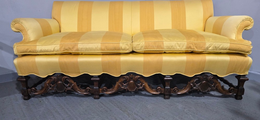 An upholstered sofa featuring yellow and gold vertical stripes with an intricately carved dark oak base decorated with shell motifs and scrolls. View III