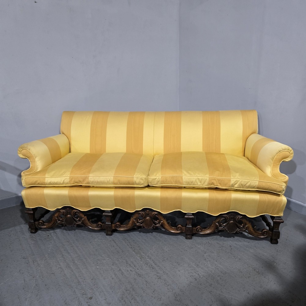 An upholstered sofa featuring yellow and gold vertical stripes with an intricately carved dark oak base decorated with shell motifs and scrolls. View V