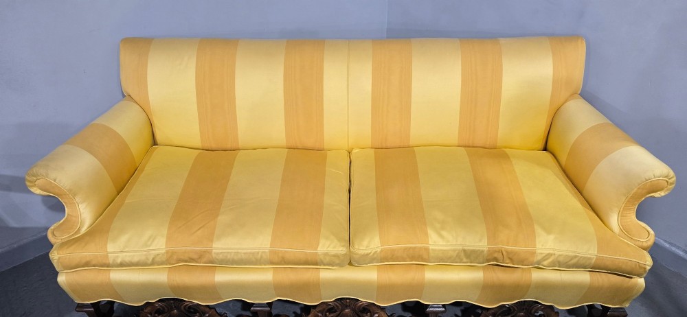 An upholstered sofa featuring yellow and gold vertical stripes with an intricately carved dark oak base decorated with shell motifs and scrolls. View VI