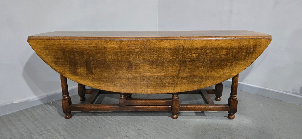 A large oval solid oak wake table featuring drop-leaf sides, turned legs, and square stretchers. View X