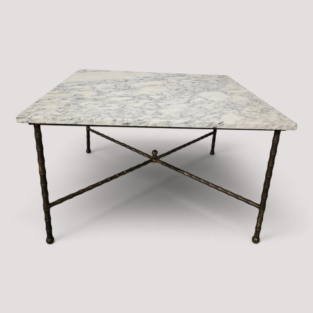 A rectangular French coffee table featuring a white veined marble top resting on a gilt brass faux-bamboo frame with an X-shaped stretcher.