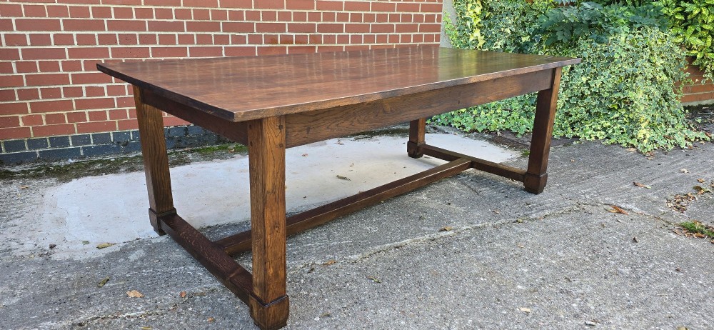 A solid warm brown French oak refectory dining table featuring a rectangular plank top, square legs, and an H-stretcher base. View V
