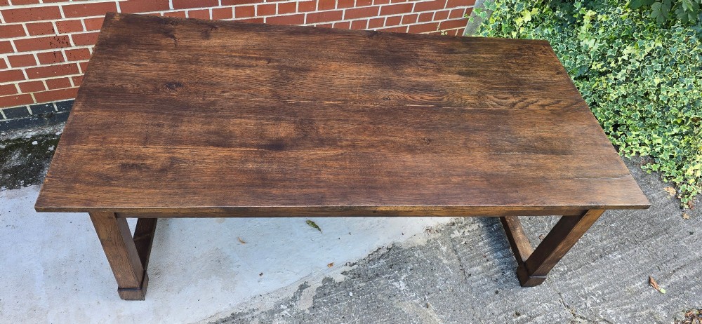 A solid warm brown French oak refectory dining table featuring a rectangular plank top, square legs, and an H-stretcher base. View XI