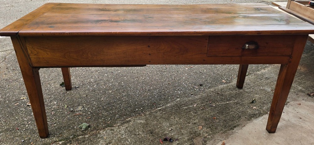 A rectangular French cherry wood refectory dining table featuring a three-plank top, side frieze drawer with metal handle, and square tapered legs. View VI